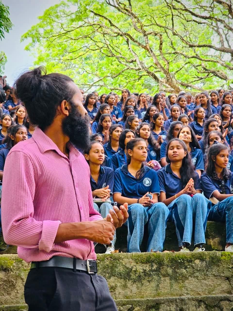 Kushan Neranjana addressing a large group of students at an outdoor history seminar